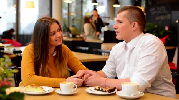 Feliz pareja enamorada beso en la cafetería - pareja cogida de la mano - café y pastel
 - Metraje, vídeo