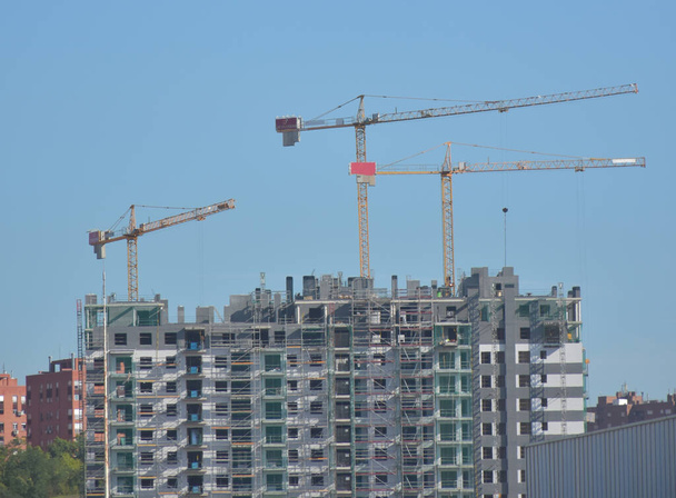 construction cranes and building houses under a blue sky - Foto, Imagem