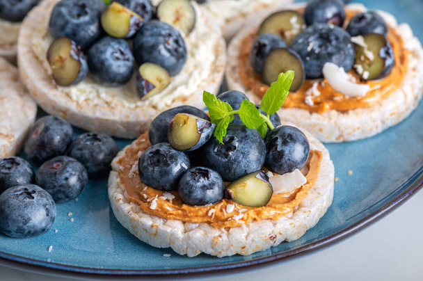 Open sandwich with blueberries. Made from rice crispbreads and peanut butter, healthy nutritious snack option, vegan food - 写真・画像