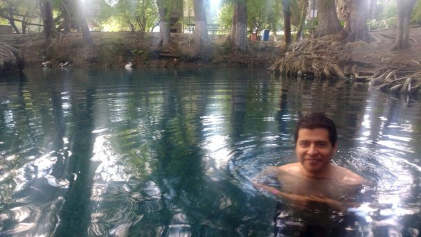 Latino adult man swims in crystal clear spring water of the Media Luna natural lagoon in the municipality of Ro Verde in San Luis Potos, Mexico relaxed enjoying his vacation and weekend - Foto, Bild