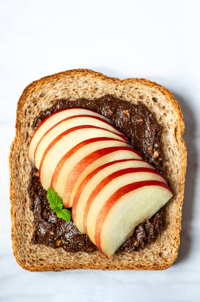 Open sandwich with sliced peach fruit and walnut. Made from wholegrain bread slice and chocolate crunchy cashew nut butter, healthy nutritious snack option - Foto, immagini
