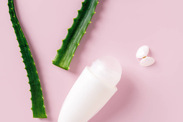 Roll on antiperspirant deodorant and fresh aloe leaves over pastel pink background. Concept of  organic cosmetics, natural toiletries, body care and personal hygiene items. Top view. - Valokuva, kuva