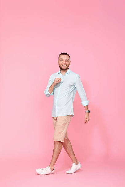 handsome happy man walks isolated on pink background. vacation summer. - Fotó, kép