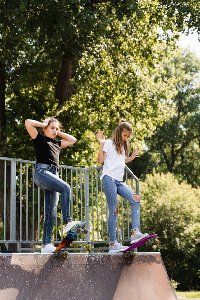 Children friendship. Girls friends ready for ride on penny board on skateboard park playground. Sports equipment for kids. Extreme lifestyle - Valokuva, kuva