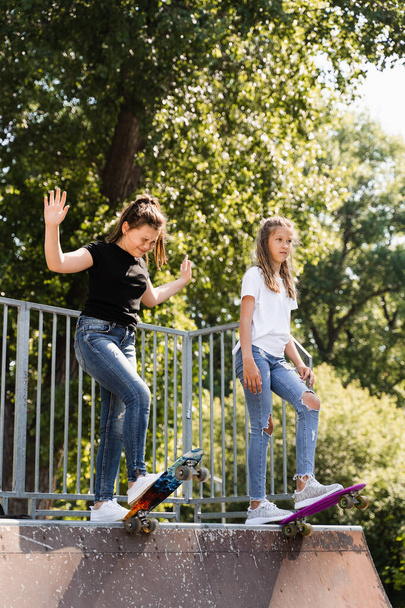Children friendship. Girls friends ready for ride on penny board on skateboard park playground. Sports equipment for kids. Extreme lifestyle - Foto, afbeelding