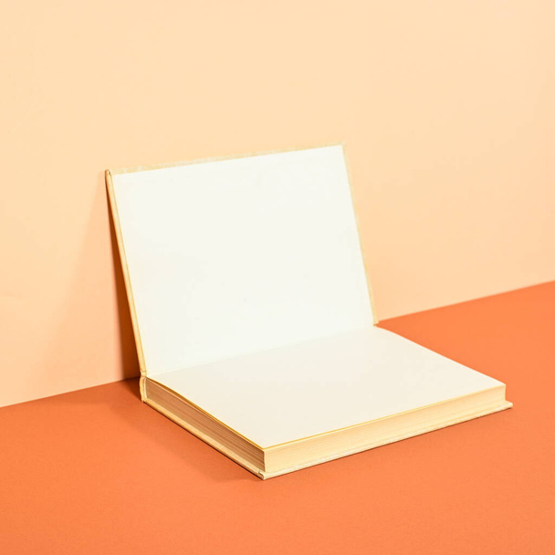 Creative backgorund with open hardcover book on two shade orange background. Flat lay copy space - Foto, afbeelding