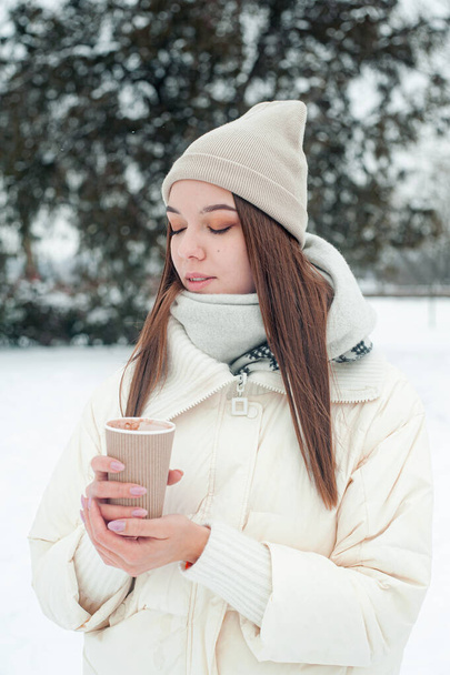 молода красива жінка в зимовому одязі п'є каву на відкритому повітрі
 - Фото, зображення
