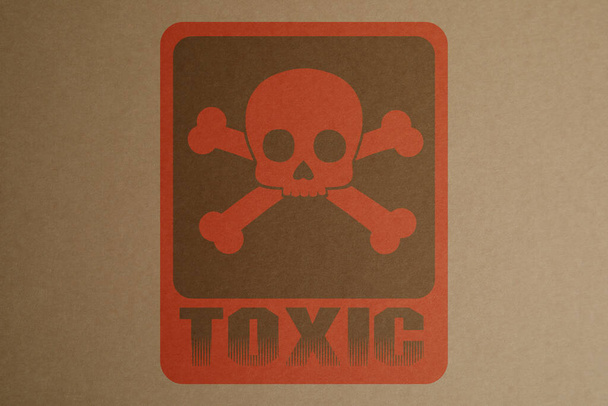 Hazard warning sign (skull-and-crossbones symbol and word TOXIC) on kraft paper, top view - Photo, image