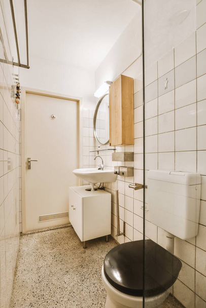 Interior of narrow restroom with sink and wall hung toilet with white walls and checkered floor - Fotografie, Obrázek