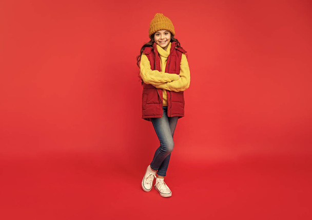female fashion model. teen girl in down vest. full length of child wearing warm clothes. express positive emotion. winter fashion. happy kid with curly hair in hat. - Foto, Imagem