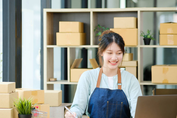 Online small business owner checking order, writing address on parcel box for delivery to customer, shipping and logistic, merchant online and seller, business owner or SME, online shopping. - Photo, Image