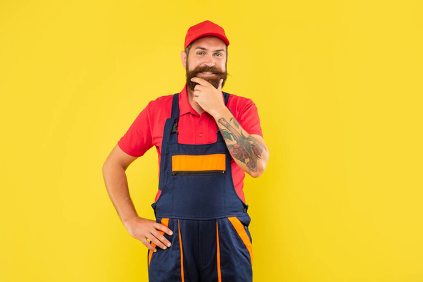 cheerful bearded man repairer in work clothes on yellow background. - Foto, afbeelding