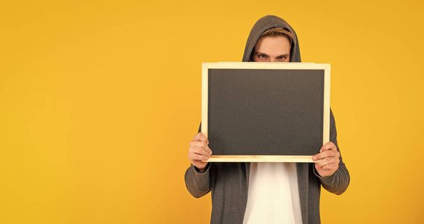 male behind chalkboard. place for useful information. advertisement copy space. your marketing design. man in hood behind blackboard. guy make announcement. - Фото, изображение