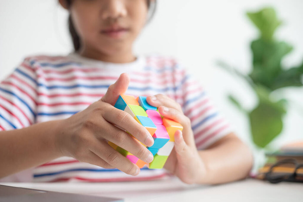 NAKHON RATCHASIMA, THAILAND - 14. Juli 2022: Asiatisches kleines süßes Mädchen mit Rubik 's Cube in der Hand. Rubik 's Cube ist ein Spiel, das die Intelligenz von Kindern steigert. - Foto, Bild