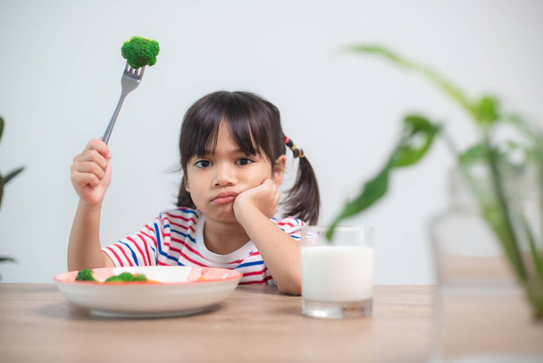 Nutrition & healthy eating habits for kids concept. Children do not like to eat vegetables. Little cute girl refuses to eat healthy vegetables. - Foto, imagen