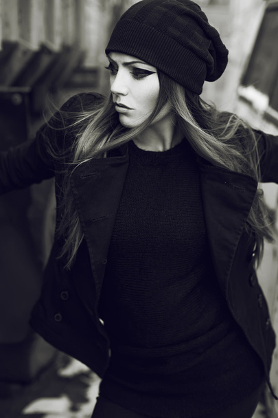 Retrato emotivo de una hermosa modelo de mujer con pelo largo y rizado y con maquillaje oscuro por la noche, con chaqueta negra
. - Foto, imagen