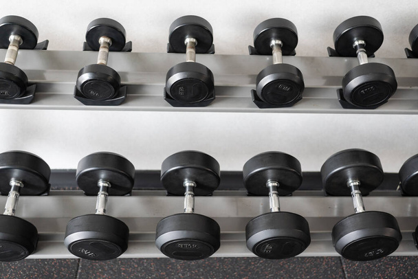 Stand with dumbbells. Sports and fitness room. Weight Training Equipment. Black dumbbell set, many dumbbells on rack in sport fitness center - Fotoğraf, Görsel
