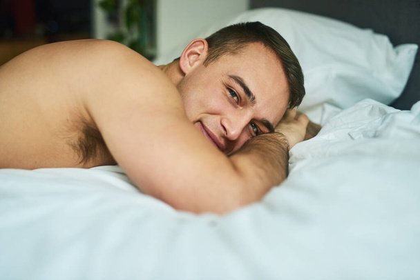 He looks good in between the sheets. a young handsome man lying in bed at home - Fotoğraf, Görsel