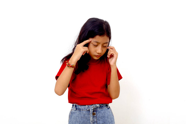 Stressed asian little girl standing while holding her head. She suffering from headache. - Foto, Imagem