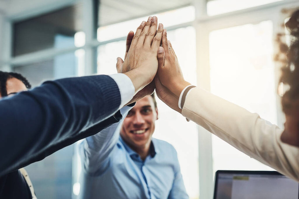 Teamwork, partnership and fun with a diverse group joining hands for a high five during team building. Colleagues uniting and showing support, community and global collaboration in an office. - 写真・画像