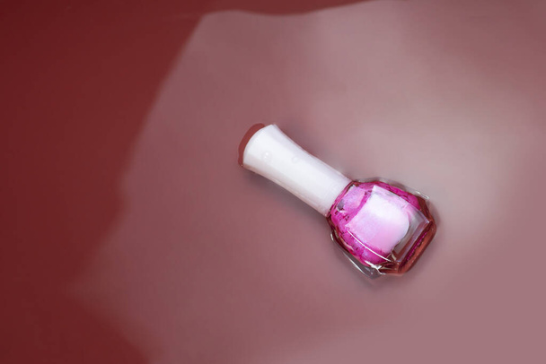 nail polish in a pink bottle On the background is water, red and pink - Fotografie, Obrázek