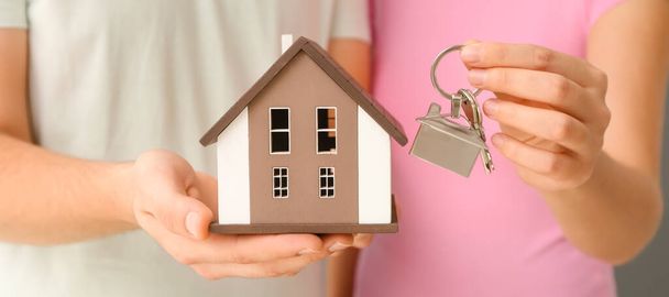 Young couple holding house model and key, closeup - 写真・画像