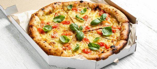 Cardboard box with delicious pizza Margherita on white wooden background - Foto, afbeelding
