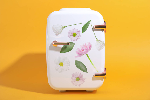 Small cosmetic refrigerator with floral print on yellow background - Fotografie, Obrázek
