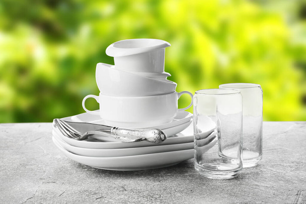 Set of clean dishes with cutlery and glasses on grunge table outdoors - Foto, Imagem