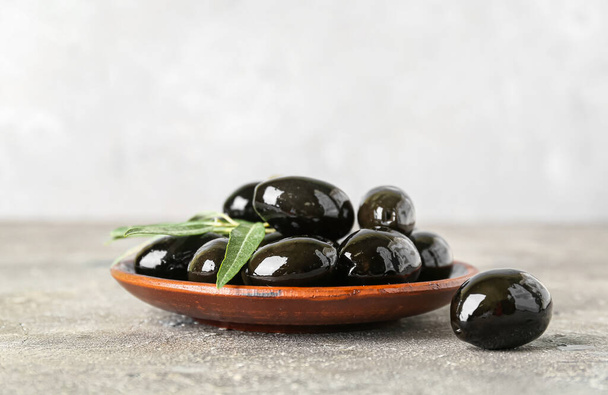 Plate with tasty black olives on table - Photo, image