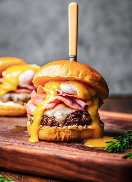 Cheese infused ground meat patty, bacon, fried egg, pickled jalapeno, Jimis secret sauce, chedder cheese. All burgers served with butter toasted bun fresh iceberg lettuce and tomatoes. - Foto, afbeelding