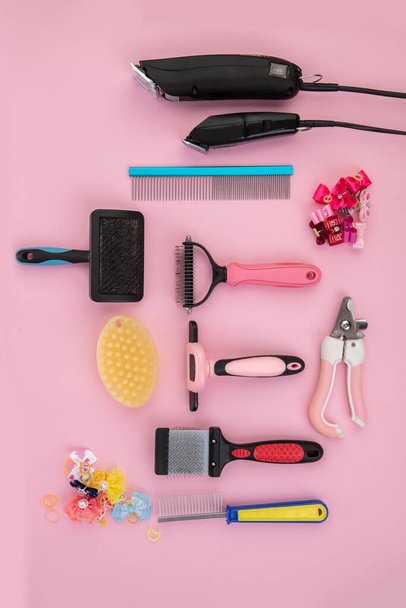 Tool for the groomer on a pink background. Dog grooming accessories. Combs and brushes for animals. View from above - Photo, image