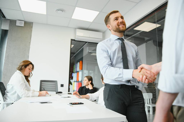 Smiling male business partners negotiators handshake start group office negotiation, company representatives welcoming shake hands at meeting getting acquainted expressing respect make financial deal. - Фото, изображение
