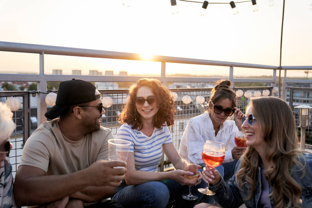 Group of friends at the rooftop party chilling together - 写真・画像