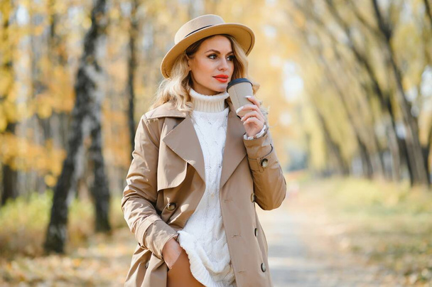 hübsche junge Frau mit Kaffeetasse im Herbstpark. - Foto, Bild