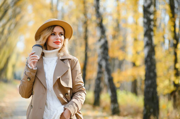 Νεαρή όμορφη γυναίκα κρατώντας κύπελλο με καφέ στο πάρκο φθινόπωρο - Φωτογραφία, εικόνα