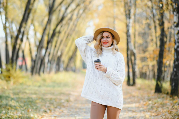 Happy smiling young woman in park on autumn day - Фото, зображення