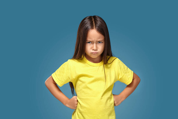 Θυμωμένο μικρό παιδί δείχνει απογοήτευση και διαφωνία για το μπλε φόντο - Φωτογραφία, εικόνα