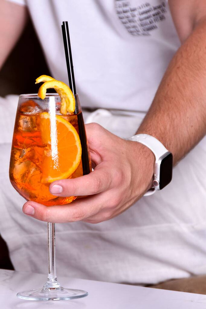 A man's hand holding a glass of Aperol cocktail - Zdjęcie, obraz