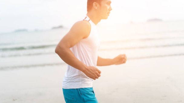 asian sport man running along seaside. running on beach with healthy toned legs body, Hamstring muscles, knee joint health active lifestyle panoramic banner background. the beach runners working out  beach - Photo, image