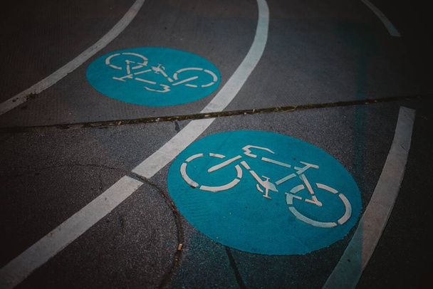 A bike lane with a blue circle and white bicycle sign during the night - 写真・画像