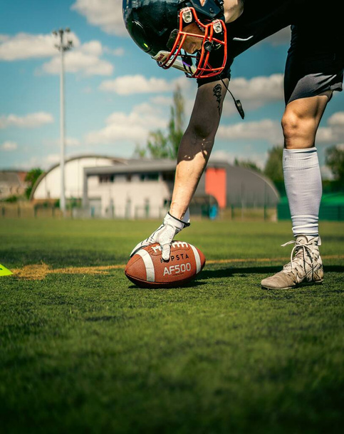 Een Amerikaanse voetballer zet een kipsta bal op het synthetische veld met witte Nike handschoenen - Foto, afbeelding