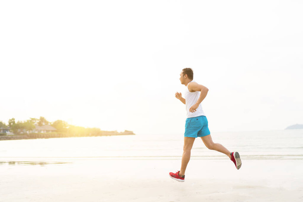 asian sport man running along seaside. running on beach with healthy toned legs body, Hamstring muscles, knee joint health active lifestyle panoramic banner background. the beach runners working out  beach - Valokuva, kuva