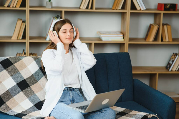 Girl with a laptop and headphones listens to music - Φωτογραφία, εικόνα