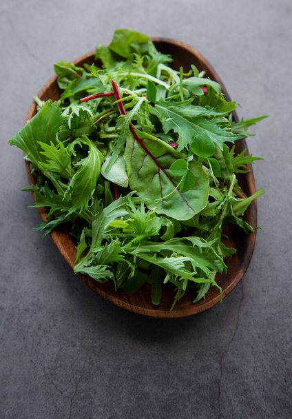 Mix of fresh green salad leaves with arugula and beets in plate on dark concrete background. Ingredient for healthy  salads - Foto, Imagen