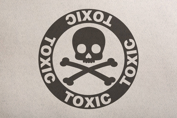 Hazard warning sign (skull-and-crossbones symbol and word TOXIC) on paper, top view - Foto, Imagen