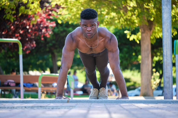 Young fit shirtless black man doing push-ups outdoors on sunny summer day. Fitness and sport lifestyle. - Foto, afbeelding