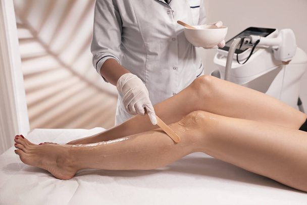 Professional cosmetologist applying gel on client's leg before laser epilation procedure in salon, closeup - Foto, Imagem