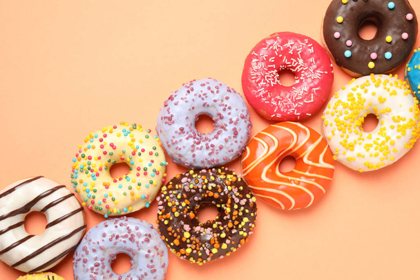 Delicious glazed donuts on orange background, flat lay - Foto, afbeelding