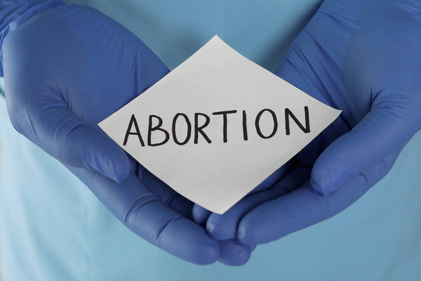 Doctor holding paper card with word ABORTION, closeup - Foto, Imagem